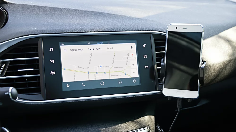 Android Auto z mapą na ekranie samochodu i telefon w uchwycie obok